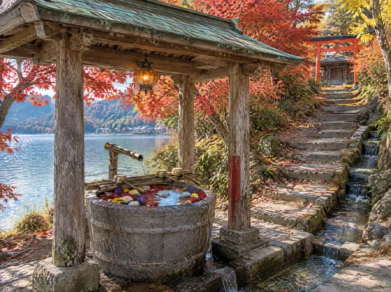 Le pavillon d'ablutions à mi-hauteur des marches ; feuilles d'érable et chrysanthèmes flottent dans un bassin de pierre en forme de baquet